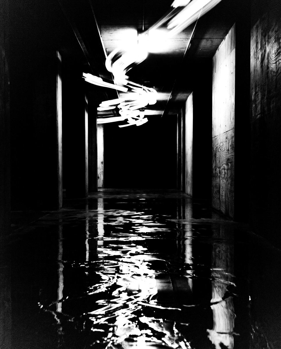 Pasillo oscuro con reflejos de luz sobre el piso mojado