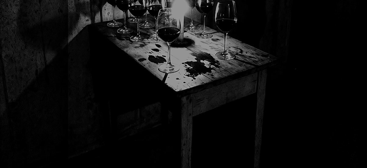 Mesa de madera con copas de vino y una vela, en blanco y negro